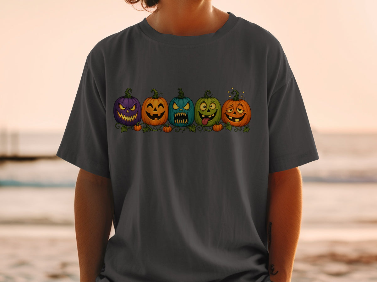 A line of five cartoon Halloween pumpkins with funny faces on a dark gray t-shirt.