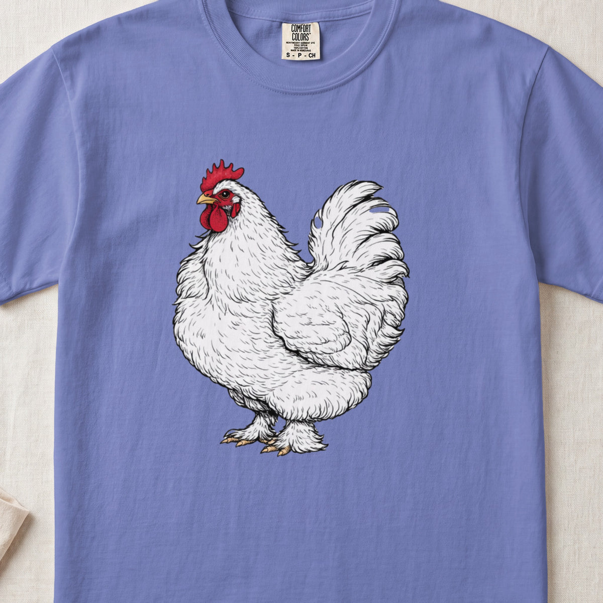 A periwinkle t-shirt featuring a detailed illustration of a white rooster centered on the chest.