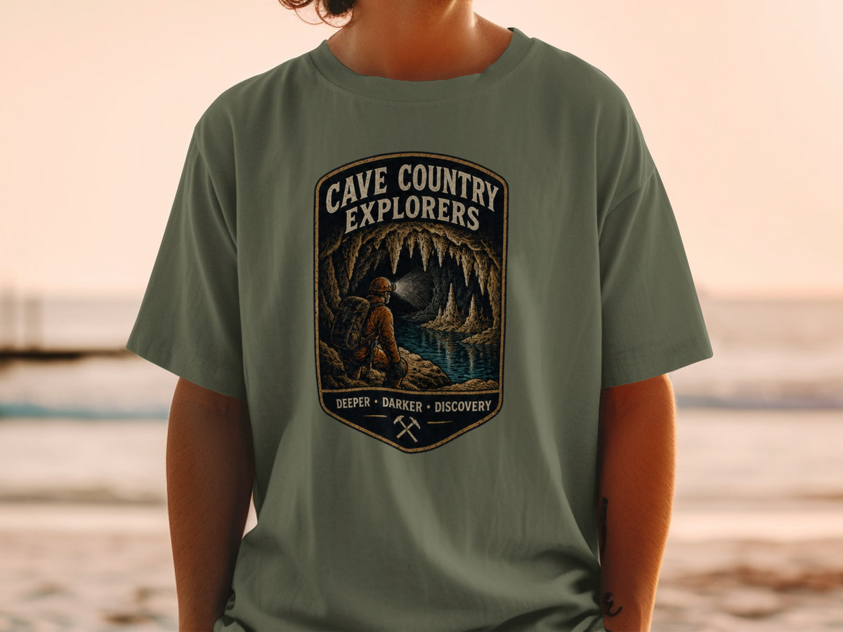 Cave Country Explorers t-shirt with spelunker exploring a cave with stalactites and a lake.