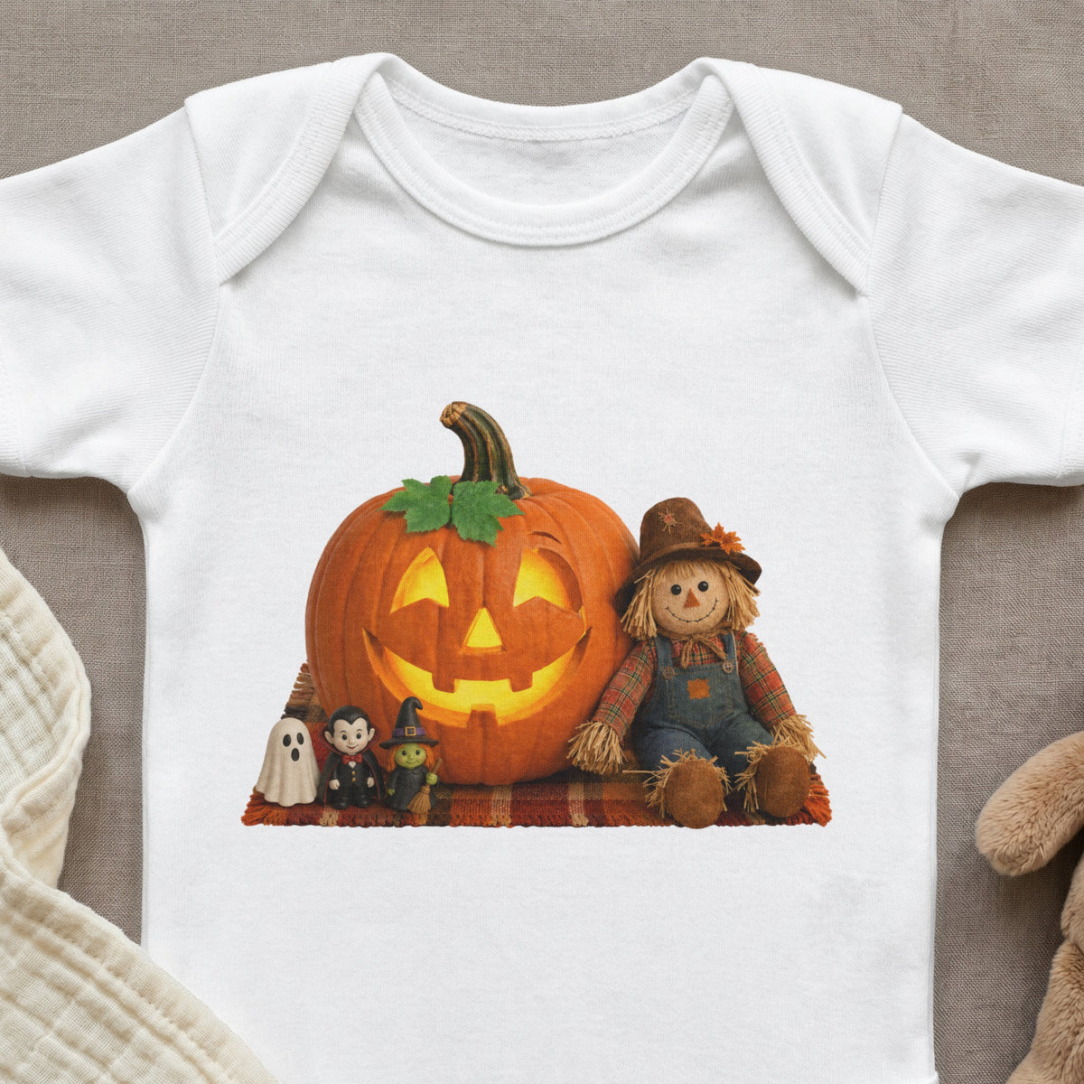 White baby onesie with Halloween graphic featuring a jack-o'-lantern, scarecrow, ghost, vampire, and witch.