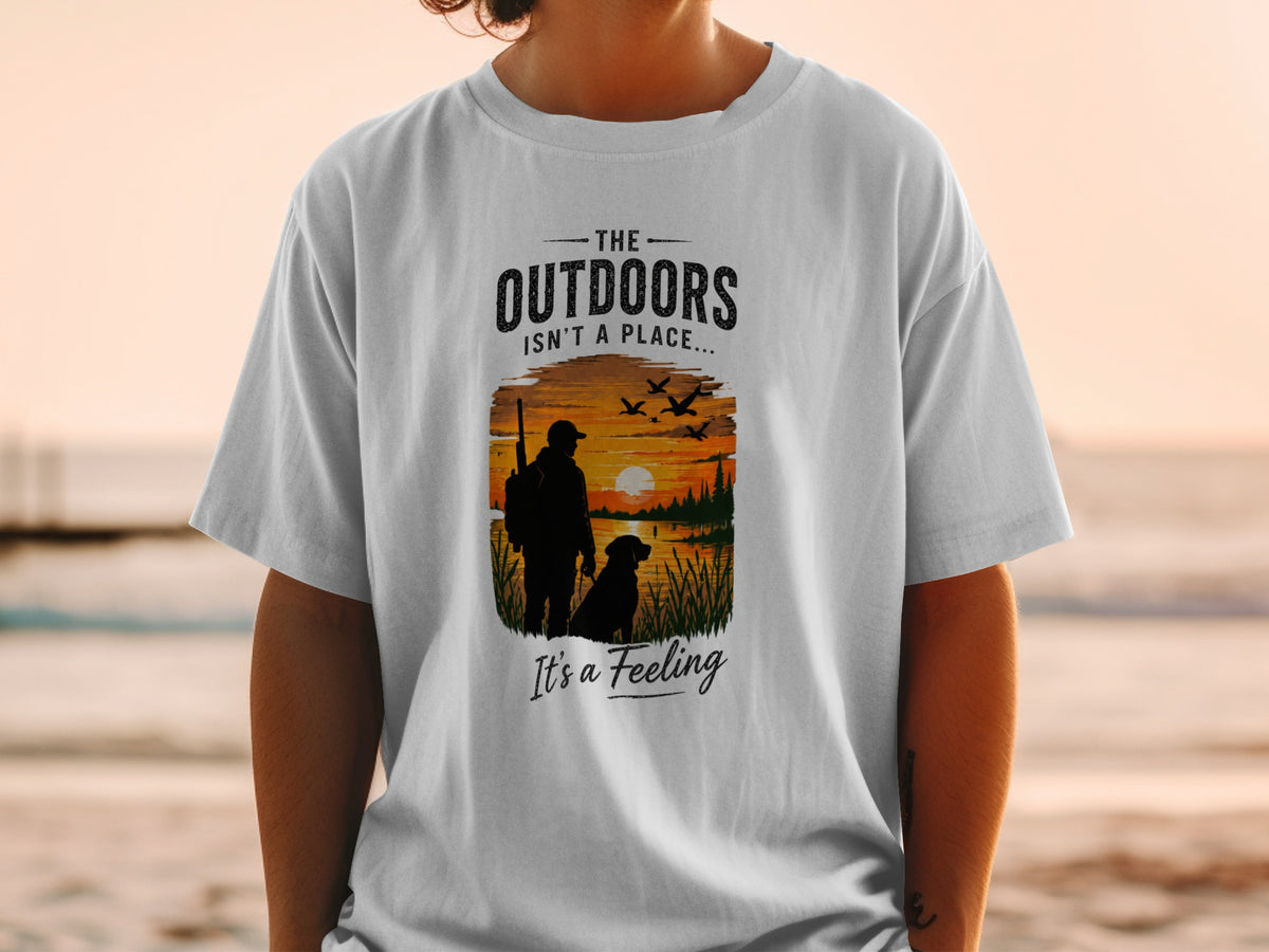 T-shirt graphic of a hunter and dog at sunset, with text "The Outdoors Isn't a Place... It's a Feeling."