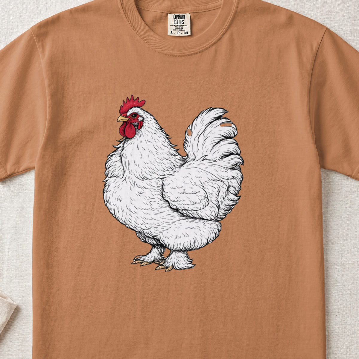 A warm-toned brown crew neck t-shirt featuring a detailed illustration of a white rooster on the chest.