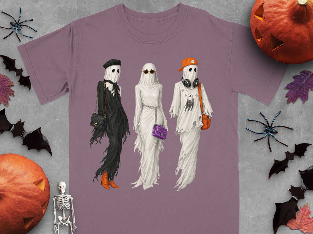 Three ghosts in Halloween costumes with accessories on a purple t-shirt.