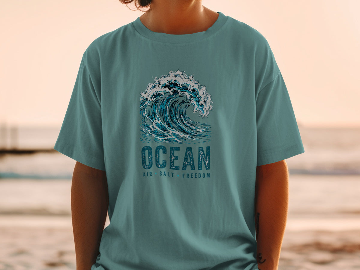 Teal t-shirt with ocean wave graphic and text "OCEAN AIR SALT FREEDOM".