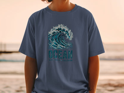 Navy t-shirt with crashing ocean wave graphic and text "OCEAN AIR SALT FREEDOM".