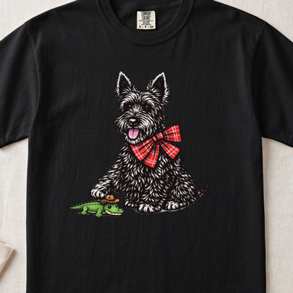 Black t-shirt featuring a graphic of a black terrier wearing a red plaid bow tie next to a small alligator wearing a cowboy hat.