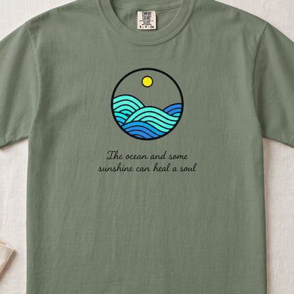 Sage green t-shirt with a round graphic of ocean waves and text reading The ocean and some sunshine can heal a soul.