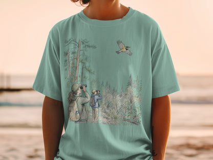 Two birdwatchers observe a bird flying over a forest landscape on a teal t-shirt.