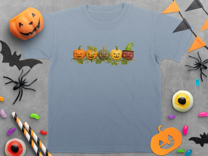 Light blue t-shirt with five smiling pumpkins and festive Halloween decorations.