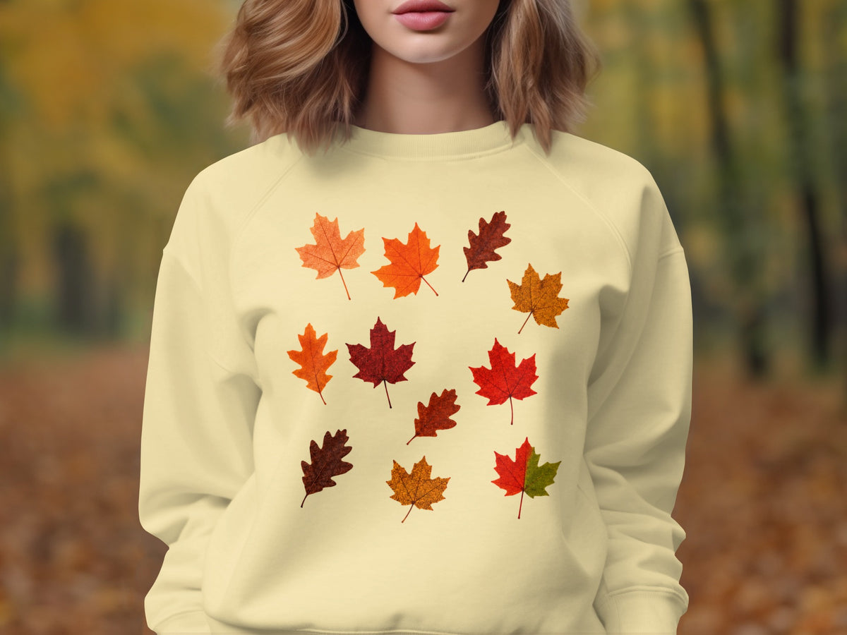 Cream sweatshirt with scattered autumn leaf graphic print.
