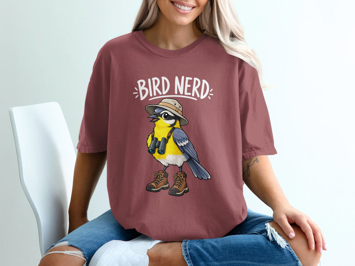 Cartoon bird with binoculars, hat, and hiking boots on a burgundy t-shirt with "BIRD NERD" text.