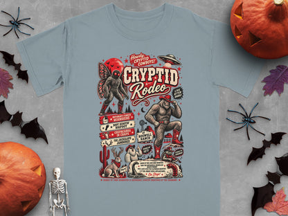 Cryptid Rodeo graphic on light blue t-shirt with Bigfoot, Mothman, and other cryptids.