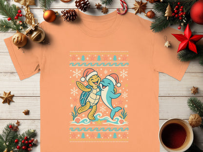 Coral t-shirt with a cartoon turtle and dolphin wearing Santa hats and hugging.