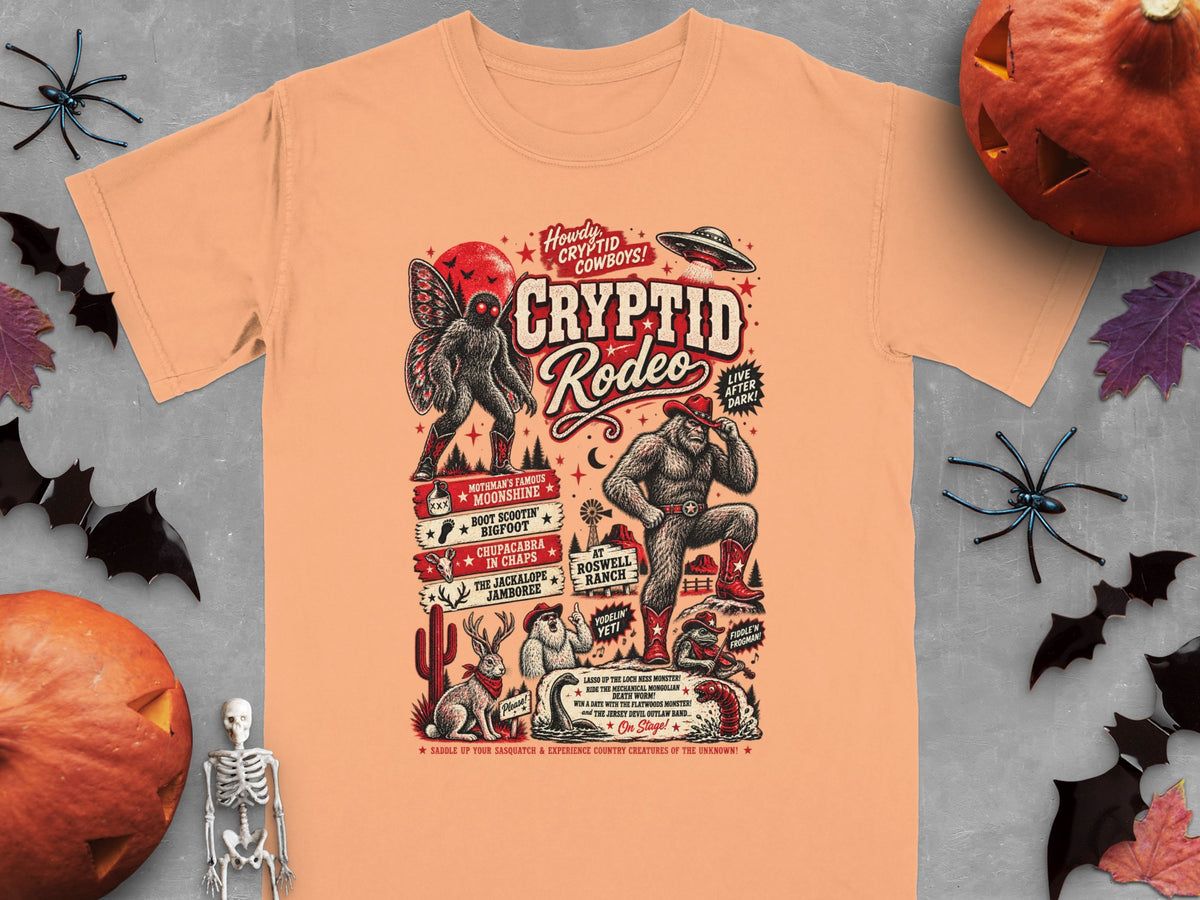 Peach t-shirt with "Cryptid Rodeo" design featuring cryptids and western elements.
