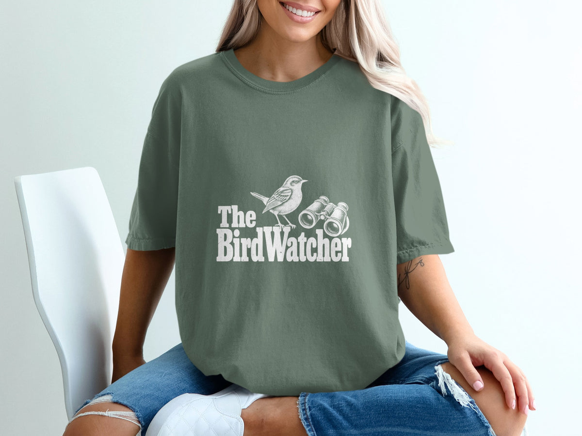Green t-shirt with white graphic of bird and binoculars, text "The Bird Watcher".