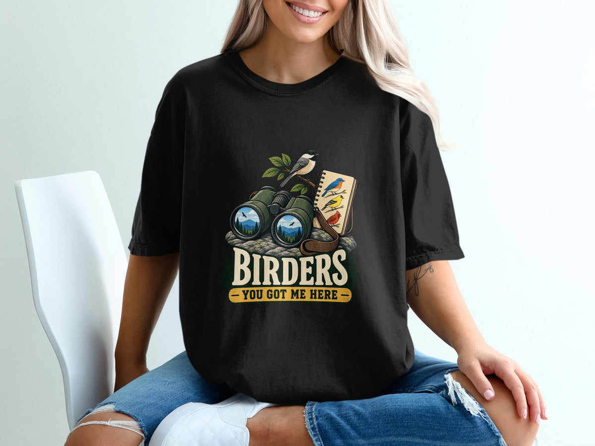 Black t-shirt graphic with binoculars, birds, and text "BIRDERS YOU GOT ME HERE".