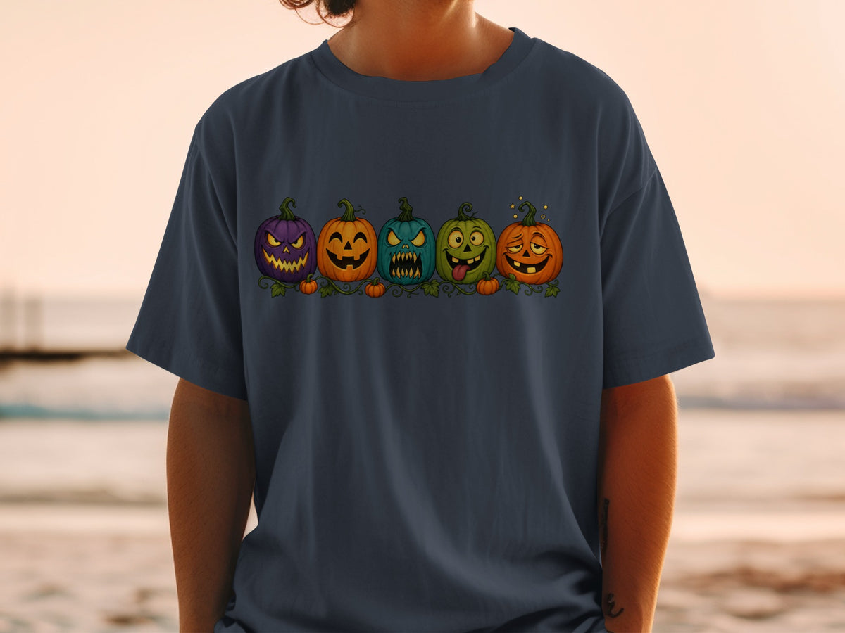 Five cartoon pumpkins with different spooky and silly faces on a navy t-shirt.
