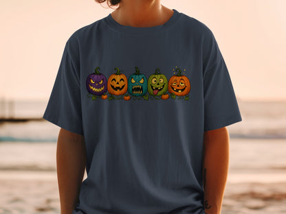 Five cartoon pumpkins with different spooky and silly faces on a navy t-shirt.