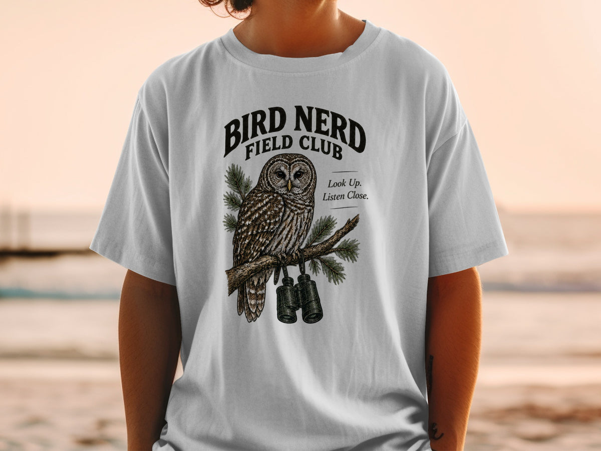 T-shirt graphic with owl, binoculars, and text "BIRD NERD FIELD CLUB".