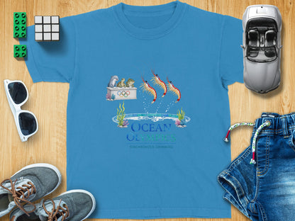 Blue t-shirt with "Ocean Olympics Synchronized Swimming" graphic featuring shrimp and sea creatures.