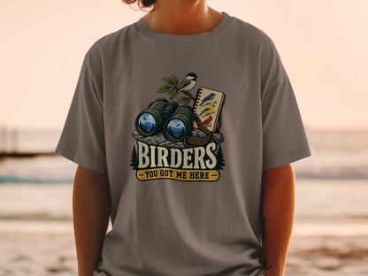 Binoculars, notebook with birds, and text "BIRDER YOU GOT ME HERE" on t-shirt.