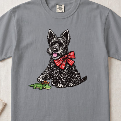 A gray t-shirt featuring an illustration of a black terrier wearing a red plaid bow tie next to a toy alligator wearing a cowboy hat.