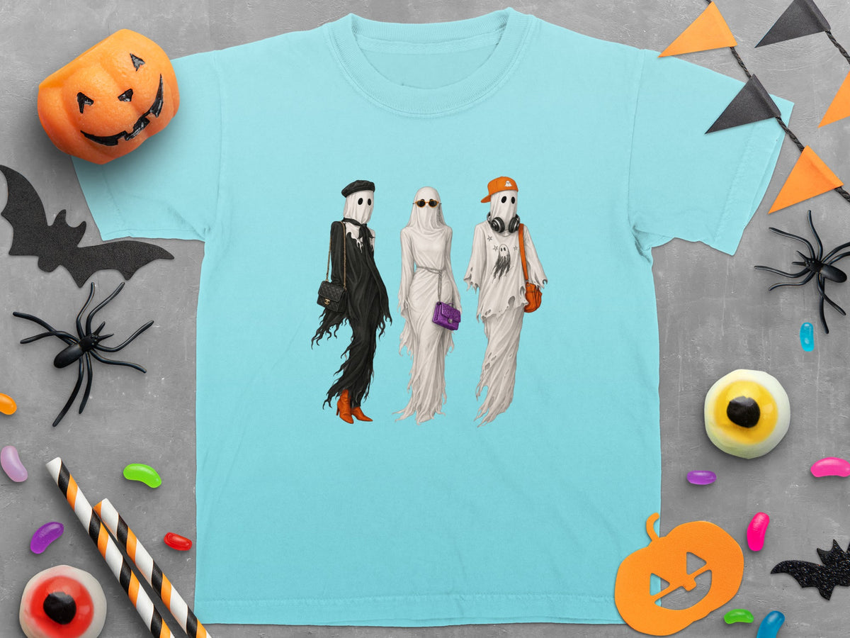 Three ghosts in fashionable outfits and Halloween decorations surround a light blue t-shirt.