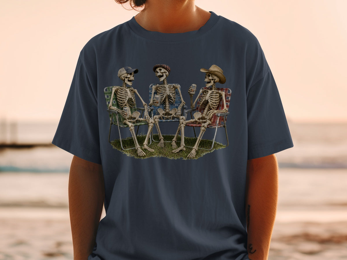 Three skeletons sit in lawn chairs on grass, holding drinks.