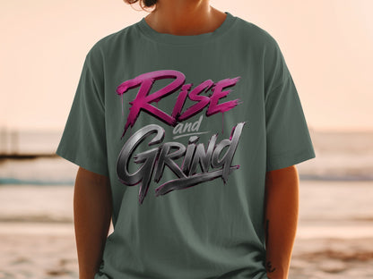 Dark green t-shirt with "Rise and Grind" text in pink and metallic silver lettering.