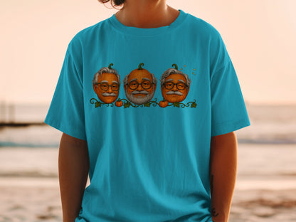 Three cartoon pumpkins with elderly men's faces on a teal t-shirt.