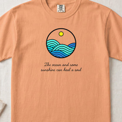 Orange crewneck t-shirt featuring a circular ocean graphic and the text The ocean and some sunshine can heal a soul.