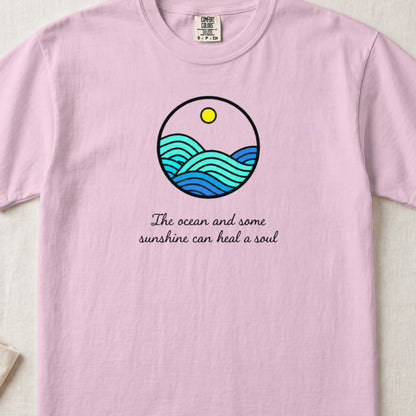 Pink t-shirt with a circular graphic of waves and sun, and text "The ocean and some sunshine can heal a soul".