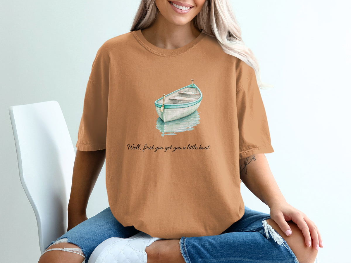 Orange t-shirt with a watercolor boat graphic and text "Well, first you get you a little boat."