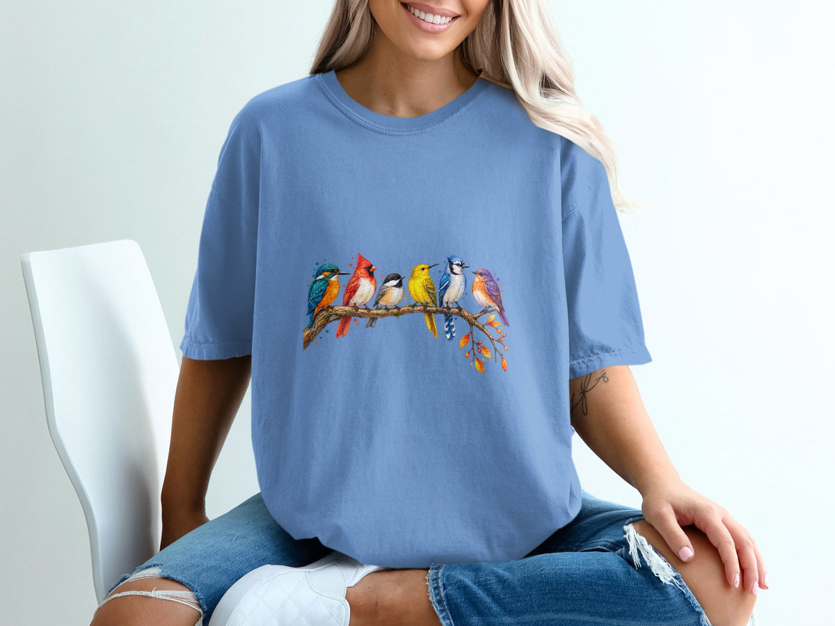 Blue t-shirt with colorful birds perched on a branch with autumn leaves.