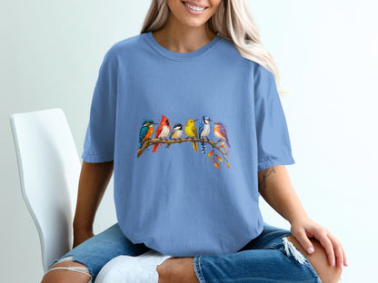 Blue t-shirt with colorful birds perched on a branch with autumn leaves.
