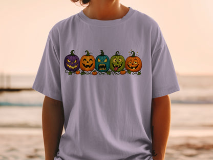 T-shirt with a graphic of five uniquely carved and colored Halloween pumpkins in a row.