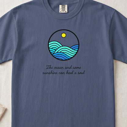 A blue t-shirt featuring a circular ocean graphic and the text The ocean and some sunshine can heal a soul.