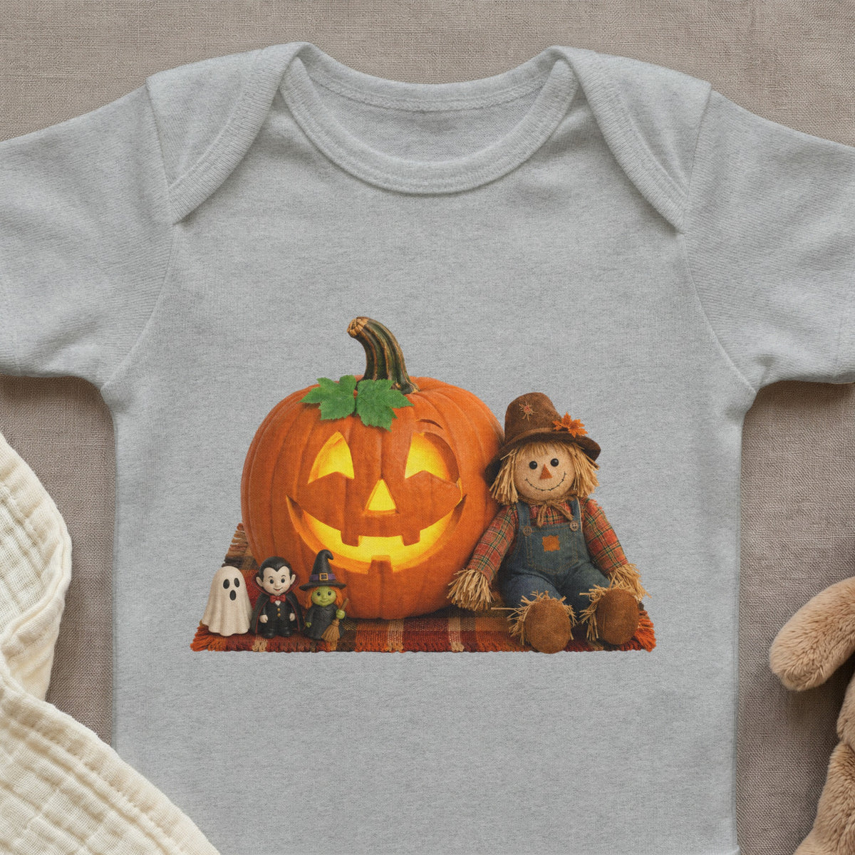 Light grey baby onesie with a Halloween graphic featuring a jack-o'-lantern, scarecrow, ghost, vampire, and witch.