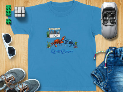 Blue t-shirt with "Claw Wrestling" sign, Olympic rings, and "Ocean Olympics" text.