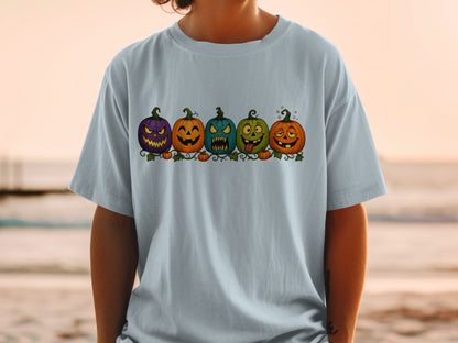 T-shirt featuring a line of five cartoon pumpkins with expressive faces.