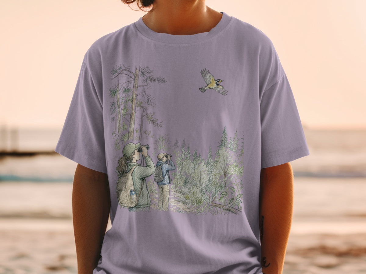 T-shirt with a watercolor illustration of birdwatchers in a forest with a flying bird.