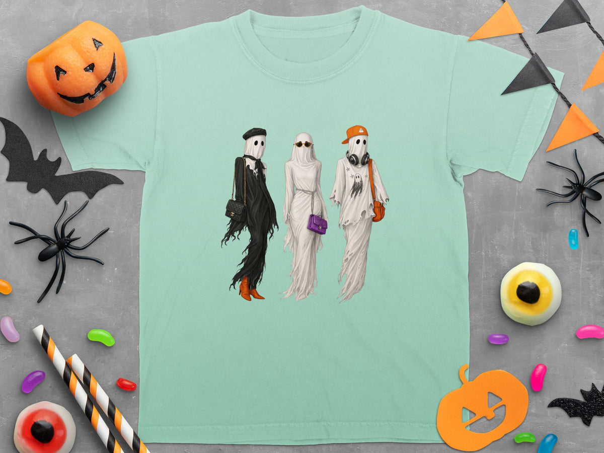 Three ghosts in stylish Halloween outfits stand on a teal t-shirt.