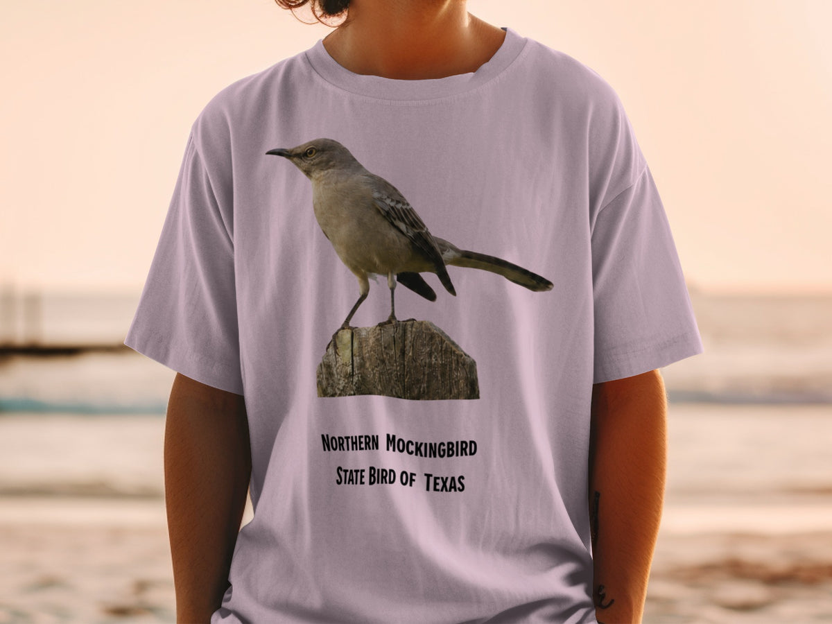 Northern Mockingbird State Bird of Texas graphic on a light purple t-shirt.