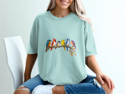 Light blue t-shirt with a watercolor print of seven colorful birds perched on a branch.