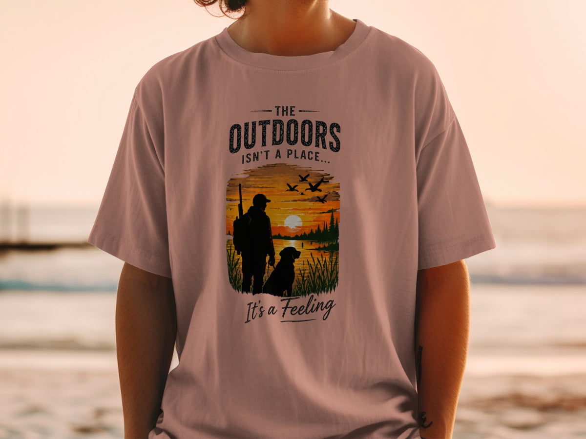 T-shirt graphic: hunter, dog, sunset, and text "The outdoors isn't a place... It's a feeling."