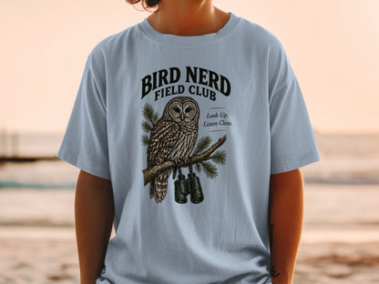 Light blue t-shirt with "BIRD NERD FIELD CLUB" text and owl graphic with binoculars.