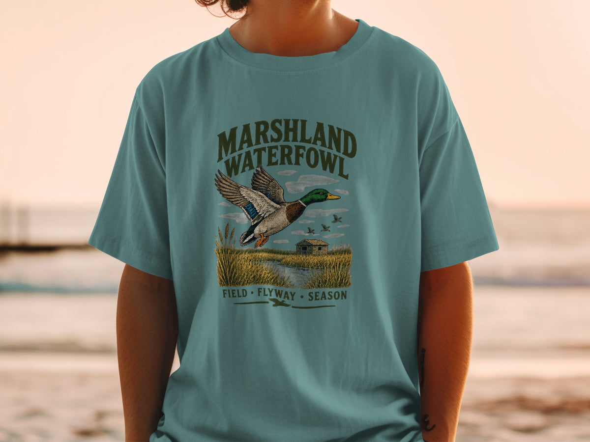 T-shirt with "Marshland Waterfowl" text, a flying duck, and a marsh scene.