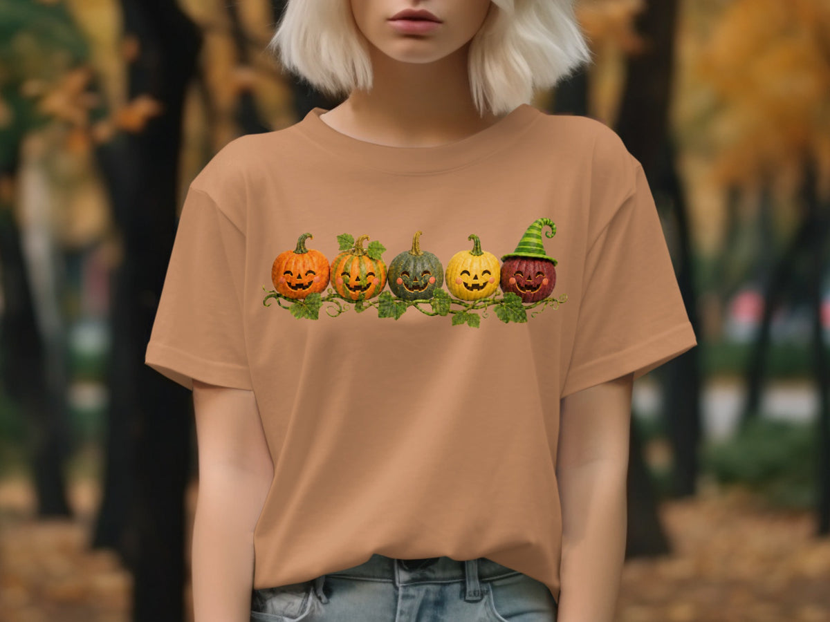 T-shirt featuring a graphic of five smiling carved pumpkins in a row with vine accents.