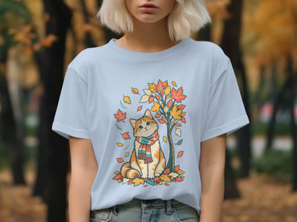 Light blue t-shirt with a cartoon cat in a scarf sitting by a fall tree.