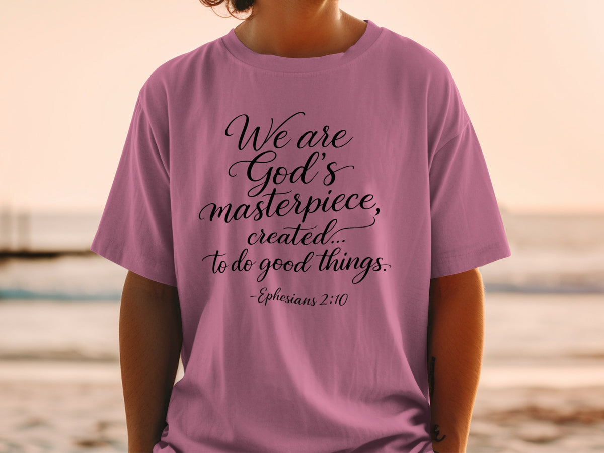 Mauve t-shirt with black script text: "We are God's masterpiece, created... to do good things. -Ephesians 2:10"